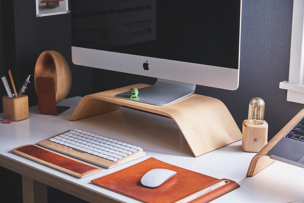 An Imac On A Wooden Stand On A Desk